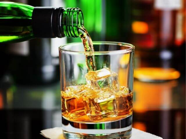 nalévání whisky do sklenice s ledem